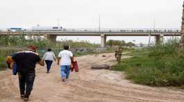 group of migrants walks towards a border