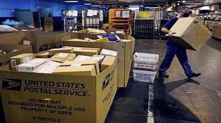 worker carries a large parcel at the United States Postal Service