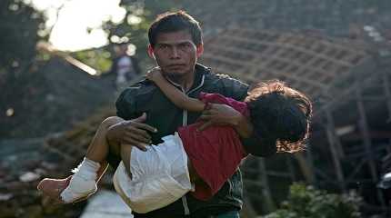 A man carries his injured daughter