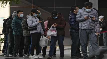 Residents stand in line to enter a store