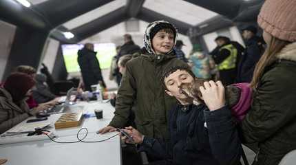 boy kisses a dog while he charges his phone