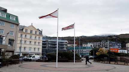 A man walks below the Union and Jersey flags