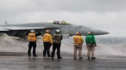 Crew members signal to a F/A-18E