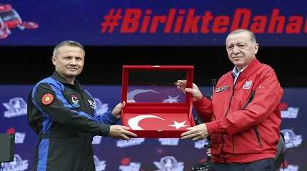 Tayyip Erdogan holds a Turkish flag with Turkish air force pilot Alper Gezeravci 