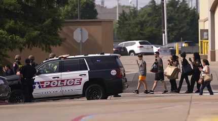 People raise their hands as they leave a shopping center