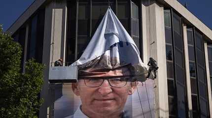 Workers remove an electoral poster Alberto Feijoo