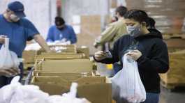 Volunteer fills a bag with food items