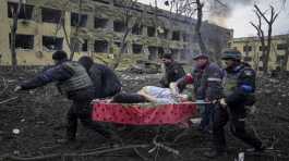 Ukrainian emergency employees carry an injured pregnant woman