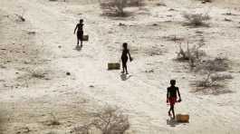 Young boys pull containers of water