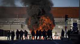 Dock workers stand in front of a burning barricade