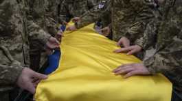 Ukrainian servicemen fold the national flag over the coffin