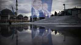 Pedestrians walk past a giant banner of Turkish President