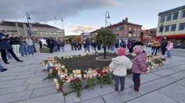  People gather around flowers and candles after a man killed